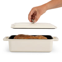 Lid being lifted from the loaf bread oven with a golden baked loaf inside