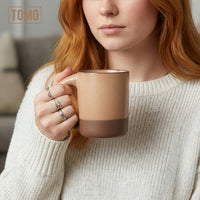 Person in a cream sweater holding a Wheat TOMO mug with both hands