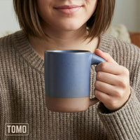 Person in a knit sweater holding a Harbor Blue TOMO mug with both hands