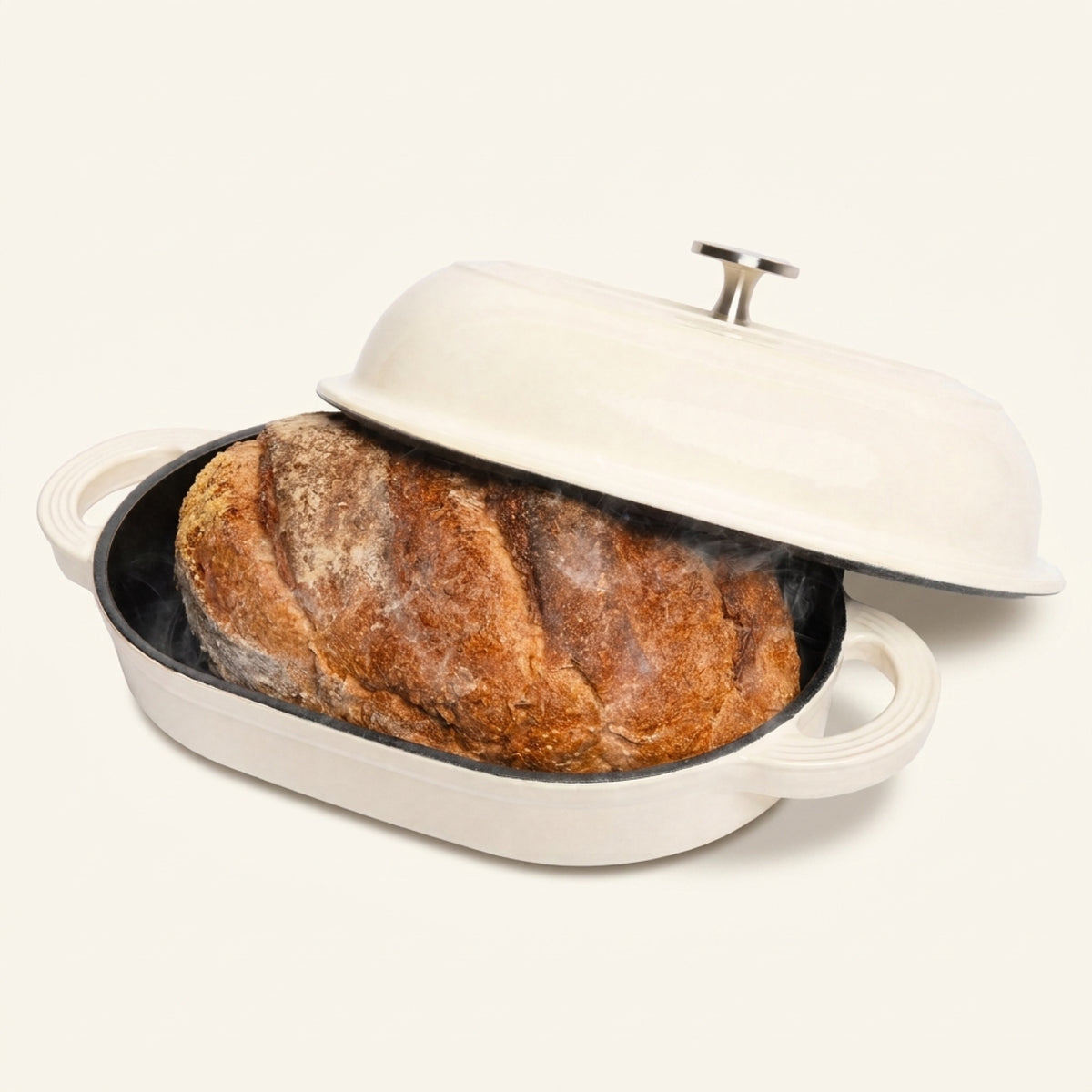 __bg__ TOMO cream enameled cast iron oval bread oven with the lid lifted off a baked sourdough batard